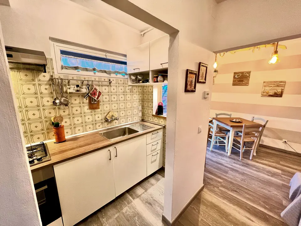 Cucina con piastrelle vintage e vista sul corridoio verso il soggiorno