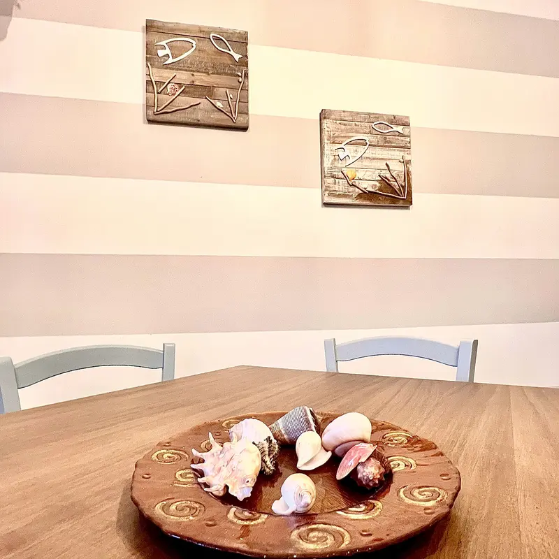 Pesci di legno decorativi appesi alla parete a righe della zona pranzo