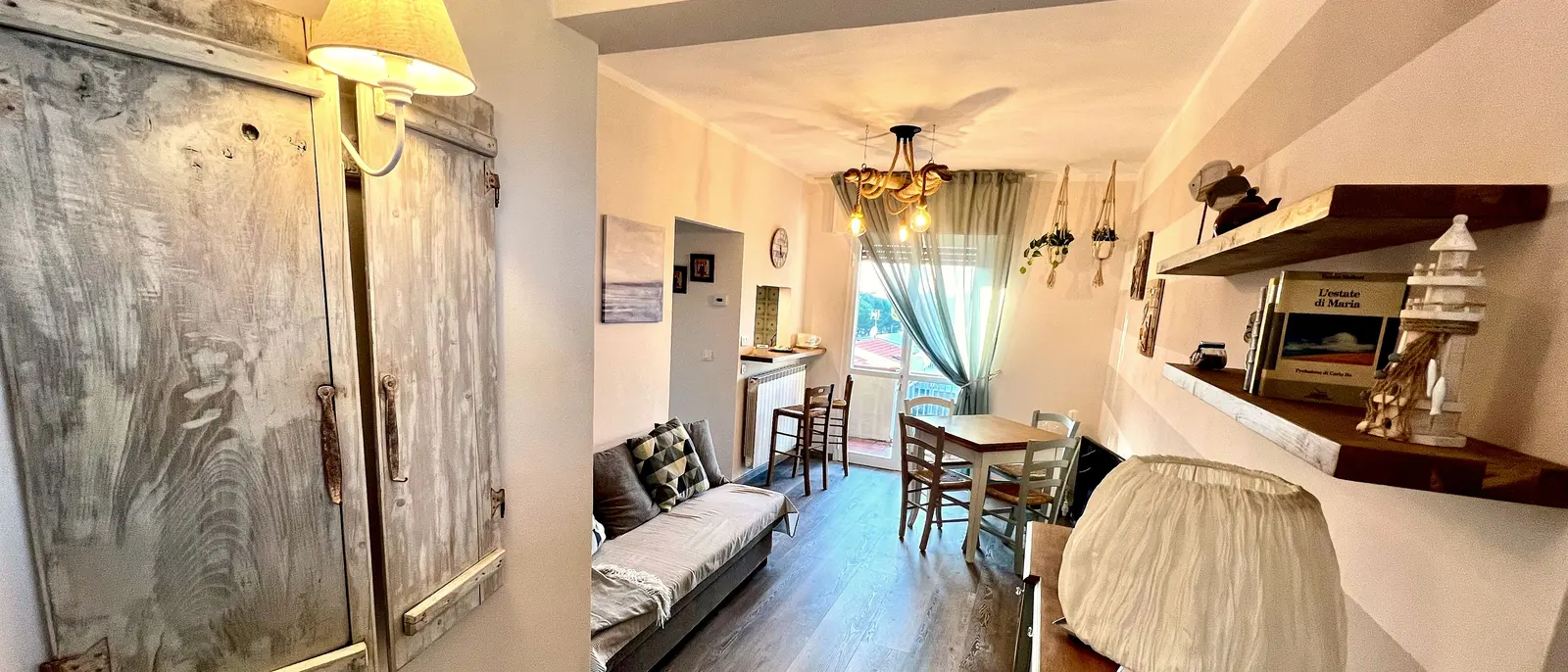 Soggiorno dell'appartamento shabby chic a Forte dei Marmi: corridoio con ante antiche appese come quadro e lampadario di corda